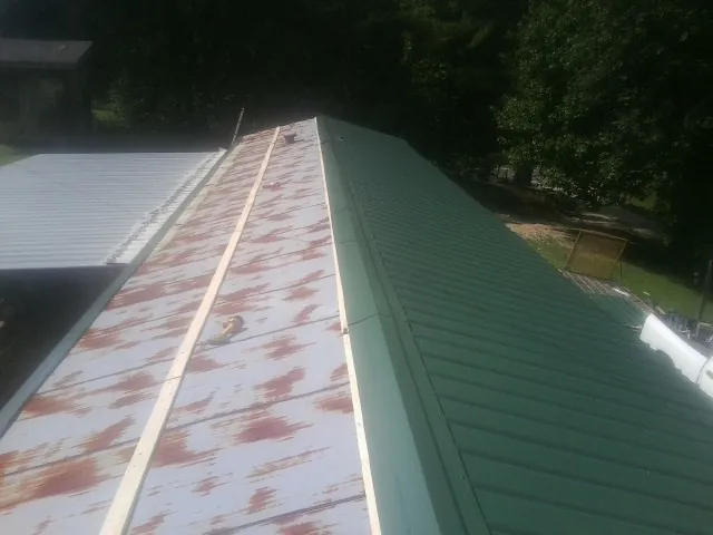 Old rusted panels beside newly installed green metal roofing — Wind Damage Roof Repair by Roofing Brothers in Lovejoy