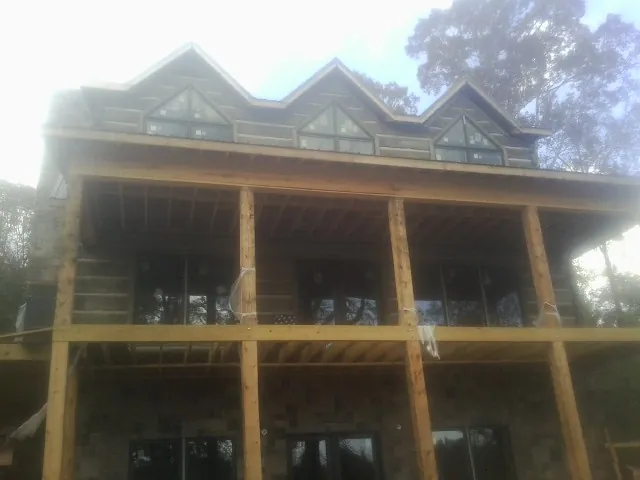 Dormers and porch framing on a large log home under construction — Roof Coating work by our crew in Lovejoy