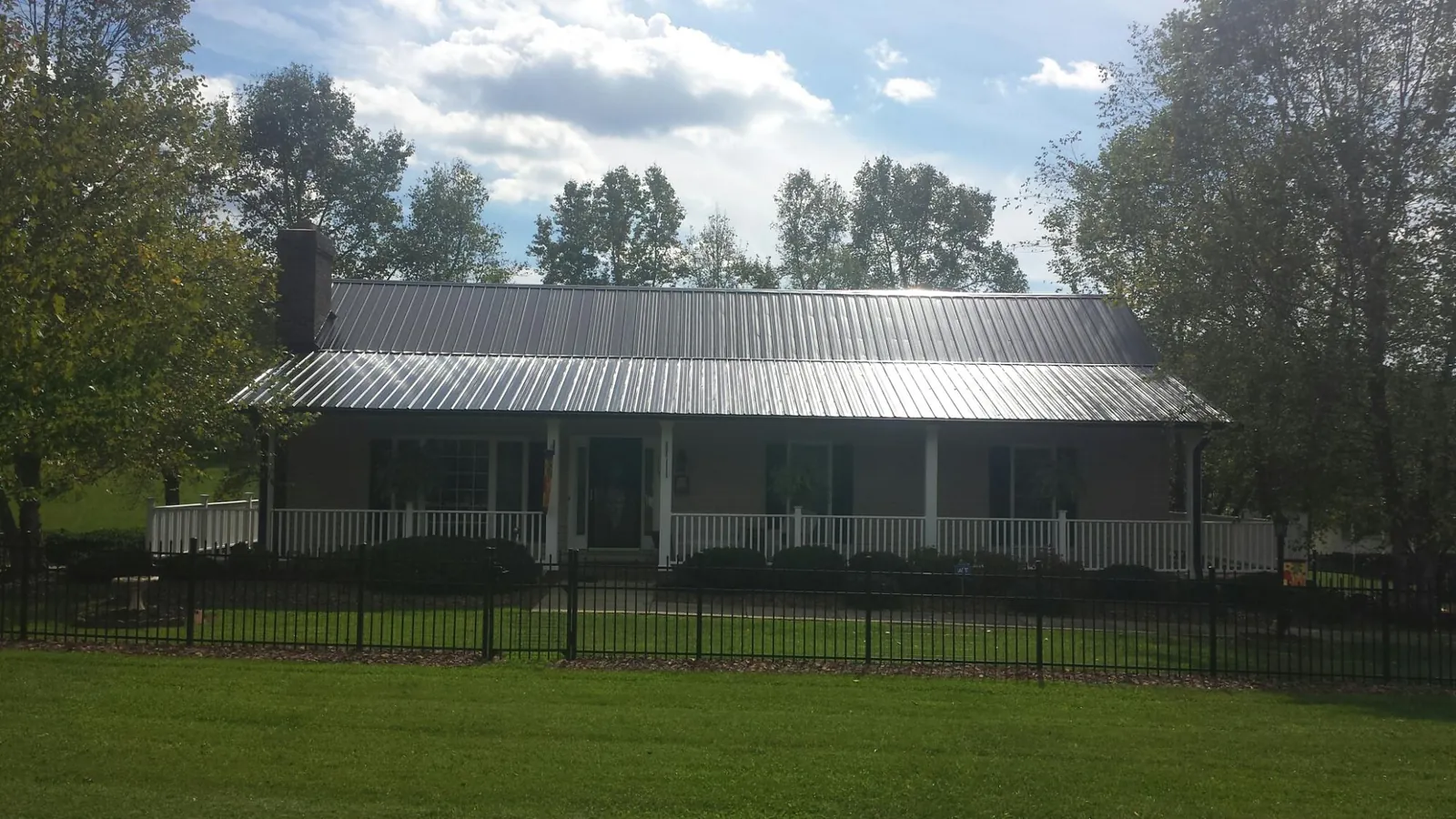 Gray metal roof on a brick ranch with a full width front porch — Gutter Guard Installation work by our crew in Lovejoy