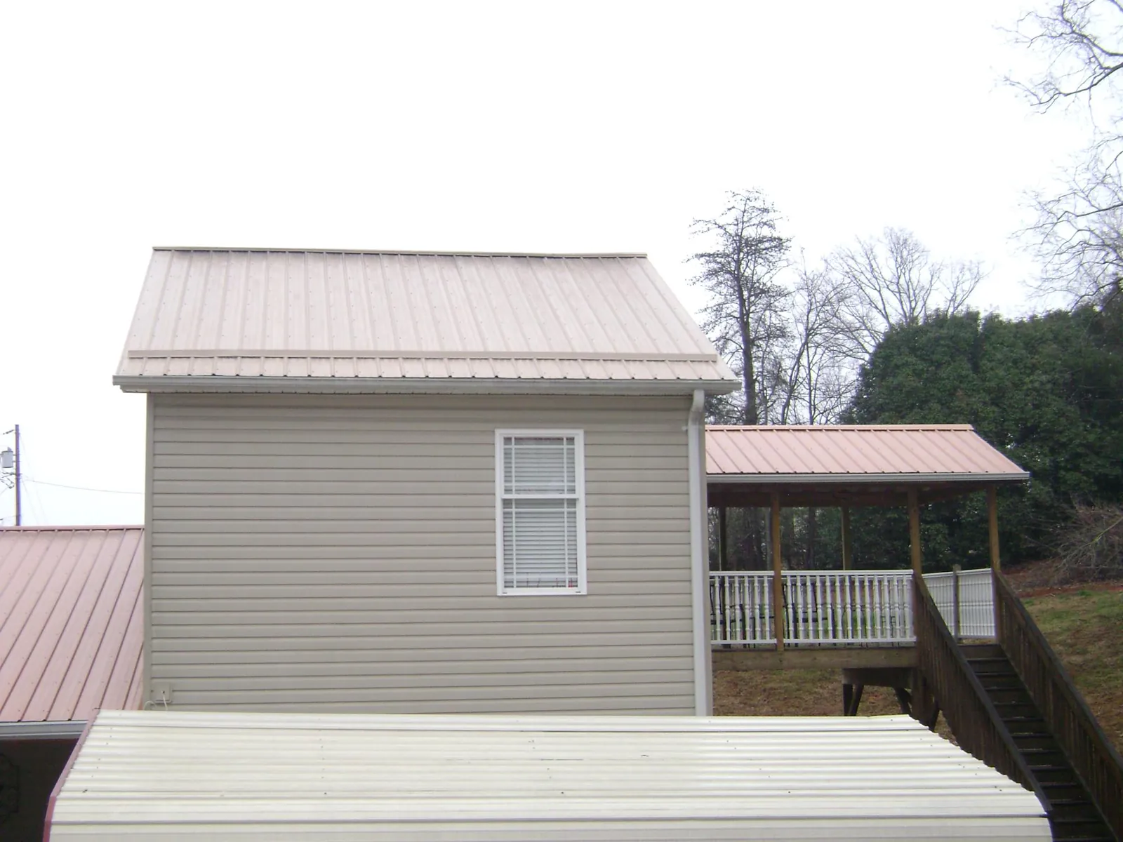 Tan metal roofs on a two story addition and attached porch, from a Roof Replacement job in Lovejoy