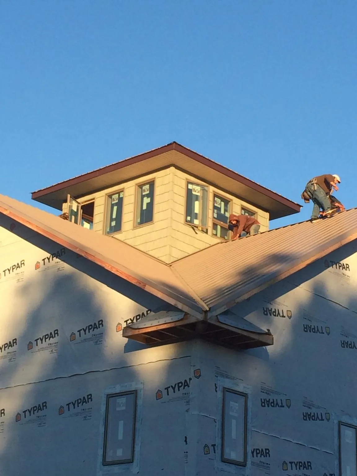 Roofers working around a rooftop cupola on a new metal roof at sunset — Roof Waterproofing in Lovejoy by Roofing Brothers